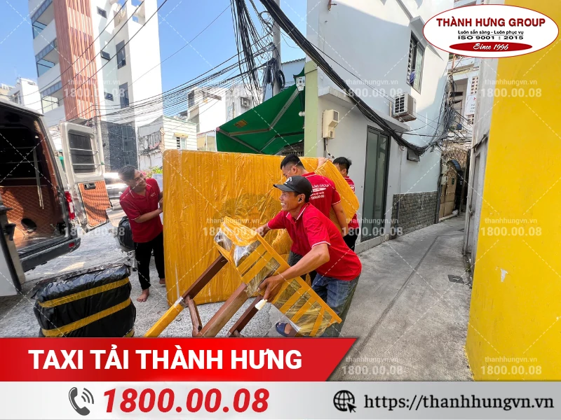 Nhân viên Thành Hưng bốc vác bàn gỗ đã được bọc lót ra xe