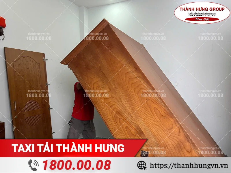 Nhân viên Thành Hưng hạ tủ gỗ lớn để xuống sàn chuẩn bị tháo dỡ