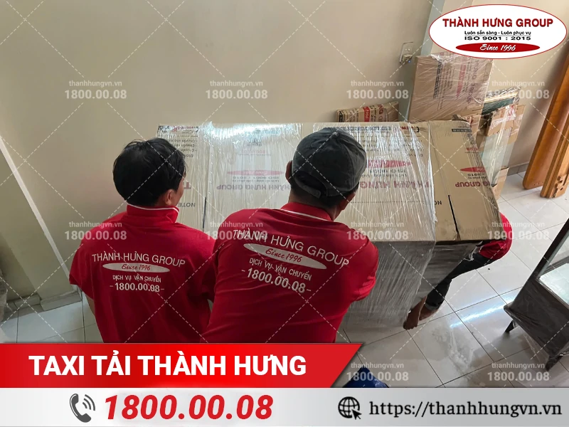 Các nhân viên phối hợp bốc xếp tủ gỗ lớn đã được bọc lót an toàn