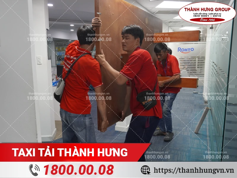 Các nhân viên Thành Hưng di chuyển bàn nguyên tấm thông qua lối đi hẹp