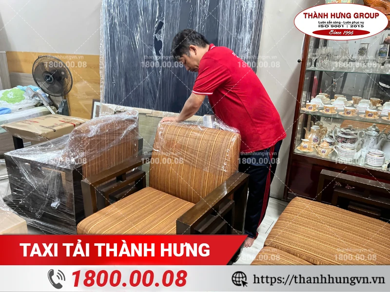 Nhân viên Thành Hưng bọc màng PE bảo vệ ghế sofa gỗ trước khi vận chuyển