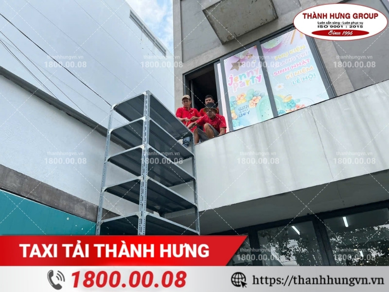Nhân viên Thành Hưng phối hợp vận chuyển kệ kho hàng qua ban công.
